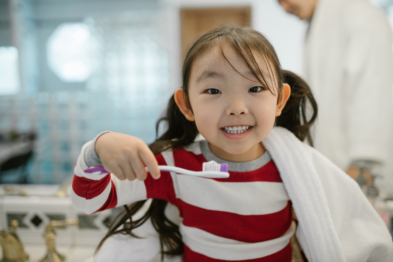 Baby girl is brushing her teeth with a baby toothpaste